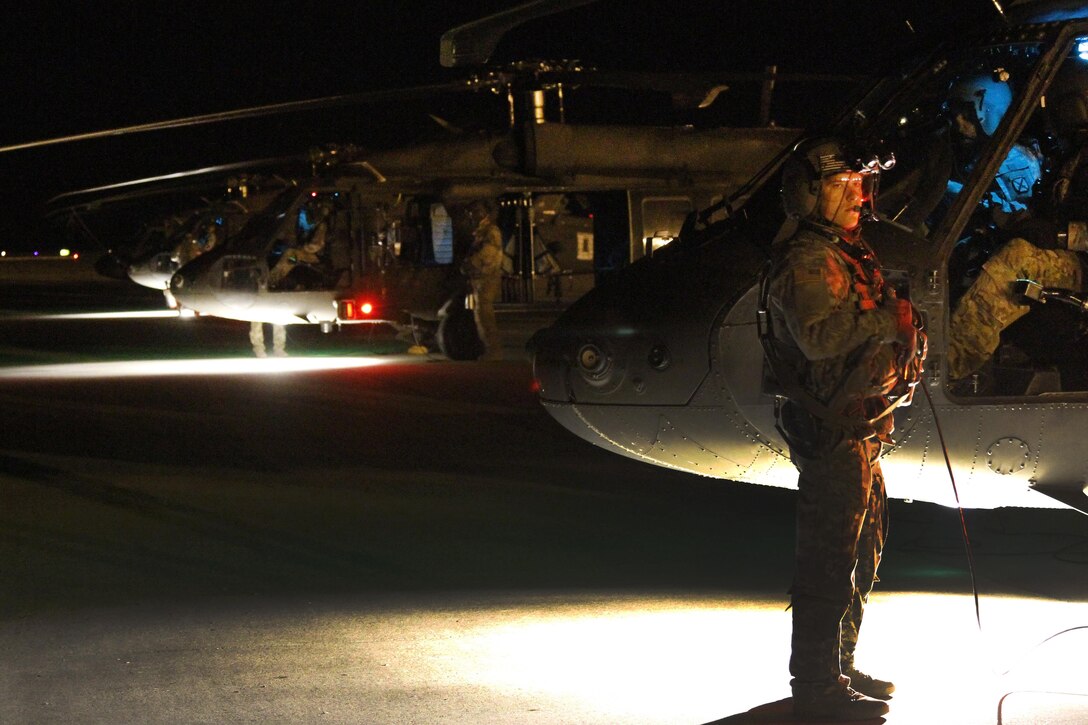 Army Spc. Matthew Carver waits next to a CH-47 Chinook helicopter to load up paratroopers to conduct an air assault training mission at the Joint Readiness Training Center in Alexandria, La., Oct. 2, 2015. Carver is a crew member assigned to the 10th Mountain Division's 10th Combat Aviation Brigade. U.S. Army photo by Sgt. 1st Class Mary Rose Mittlesteadt 