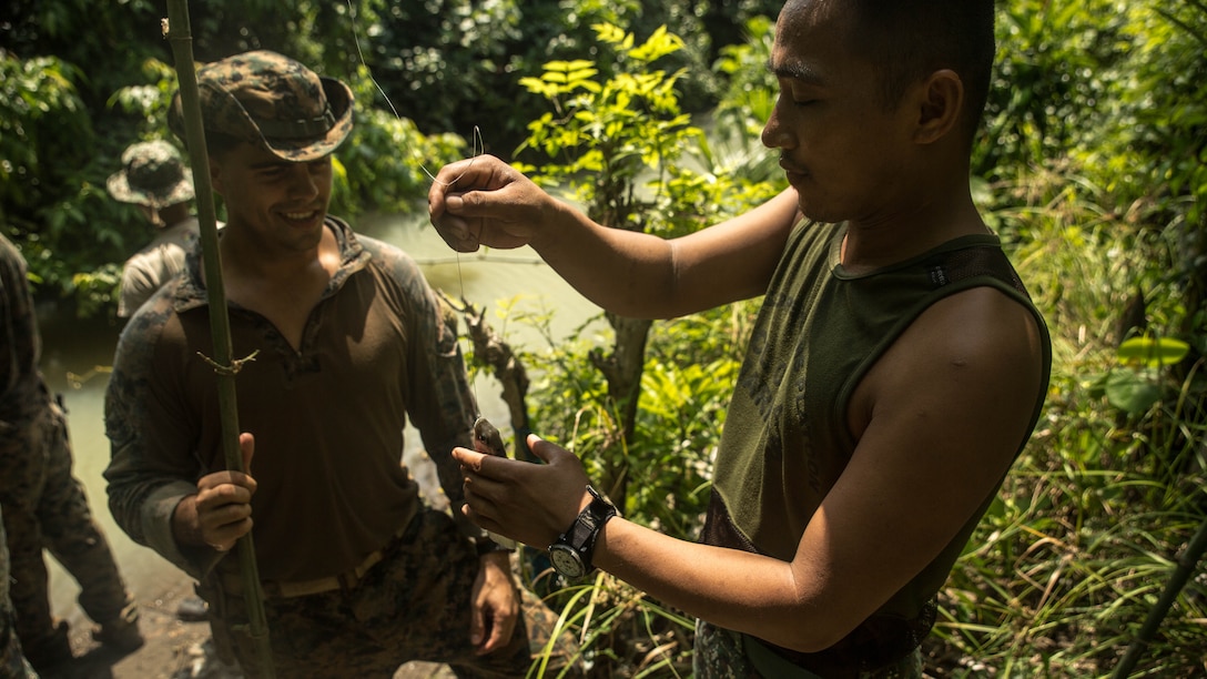 Philippine Marine Corps Cpl. Elmer Addatu, right, grabs a fish of the line of U.S. Marine Corps Cpl. Lucas Fernandez’s improvised fishing pole during jungle survival training at Ternate, Philippines, Sept. 30, as part of Amphibious Landing Exercise 2015. The Marines learned basic jungle survival skills, such as building a fire, finding sources of fresh water and catching food. 