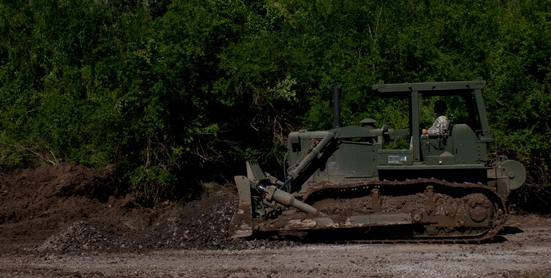 U.S. Army Reserve Sgt. Nicholas Chiodini, heavy equipment operator with the 712th Engineer Support Company (Horizontal) out of York, S.C., spreads gravel to improve traction on slip four at Fort Chaffee, Ark., Aug. 1 during Operation River Assault 2015. The unit cleared the slips of 2 to 4 inches of mud and debris and laid gravel to ensure vehicles had access to the river for the culminating event, the gap crossing. (U.S. Army photo by Staff Sgt. Debralee Best)