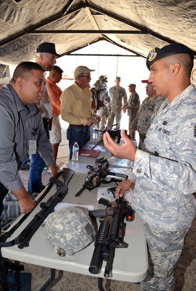 Staff Sgt. Gabriel Saucedo of the 433rd Security Forces Squadron discusses some of the weapons used by security forces Airmen with 433rd Airlift Wing Honorary Commander John Smith during a base tour Oct. 3, 2015 at Joint Air Base San Antonio-Lackland. Smith, who works for the Department of Homeland Security, and other local civic leaders were able to handle and try on a variety of equipment used by firefighters, security forces and explosive ordnance disposal teams within the wing during the tour. (U.S. Air Force photo/Tech. Sgt. Lindsey Maurice)
