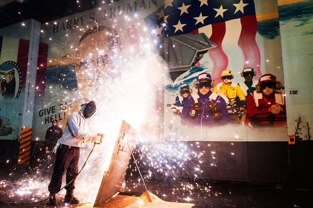 Navy Petty Officer 3rd Class A. Humphrey cuts a sheet of metal with a torch during a general quarters drill in the hangar bay of the aircraft carrier USS Harry S. Truman in the Atlantic Ocean, Oct. 3, 2015. U.S. Navy photo by Petty Officer 2nd Class K. H. Anderson