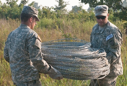 U.S. Army Reserve Spcs. Johnathan O'Connell and Jonathan Du Bois, combat engineers with the 309th Engineer Company (Mobility Augmentation), carry concertina wire to use in emplacing a hasty frat fence during Sapper Stakes 2015 at Fort Chaffee, Ark., Sept. 1. (U.S. Army photo by Staff Sgt. Debralee Best)