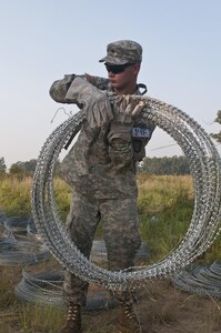 U.S. Army Reserve Spc. Tyler Chatterton, combat engineer, 402nd Engineer Company (Sapper), carries concertina wire to use in emplacing a hasty frat fence during Sapper Stakes 2015 at Fort Chaffee, Ark., Sept. 1. (U.S. Army photo by Staff Sgt. Debralee Best)