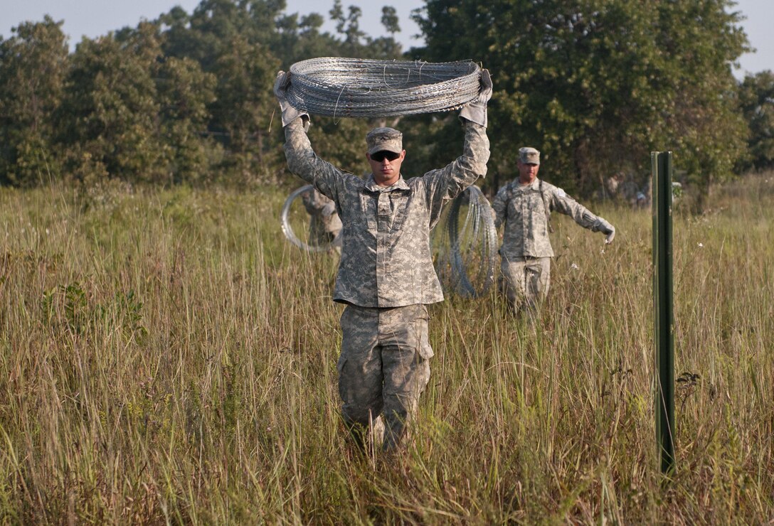 U.S. Army Reserve Cpl. Gary Coggins, combat engineer, 348th Engineer Company, carries concertina wire to use in emplacing a hasty frat fence during Sapper Stakes 2015 at Fort Chaffee, Ark., Sept. 1. (U.S. Army photo by Staff Sgt. Debralee Best)