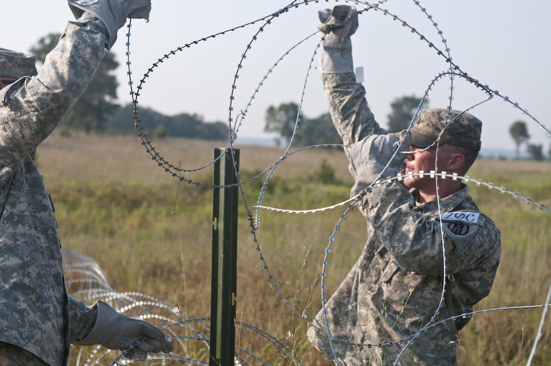 U.S. Army Reserve Cpl. Johnathan Doolan, combat engineer, 348th Engineer Company works with a teammate to emplace concertina wire on a picket while constructing a hasty frat fence as part of Sapper Stakes 2015, Sept. 1. This year's competion, held at Fort Chaffee, Ark., pitted 20 combat engineer teams against each other in physical and mental engineer and Soldier tasks. (U.S. Army photo by Staff Sgt. Debralee Best)