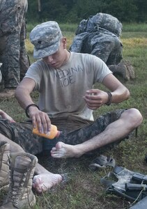 U.S. Army Reserve Spc. Jesus Medina, combat engineer, 386th Engineer Company (Route Clearance) out of Las Vegas, applies foot powder between the 2.1 mile run and 4.1 mile ruck march of the nonstandard Army physical fitness test, the first event of Sapper Stakes 2015, at Fort Chaffee, Ark., Aug. 30. (U.S. Army photo by Staff Sgt. Debralee Best)