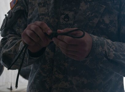 A Soldier inspects a knot before being evaluated based on its accuracy during Sapper Stakes 2015, Aug. 30 at Fort Chaffee, Ark. Competing teams were scored on their ability to correctly tie six of eight knots. (U.S. Army photo by Staff Sgt. Debralee Best)