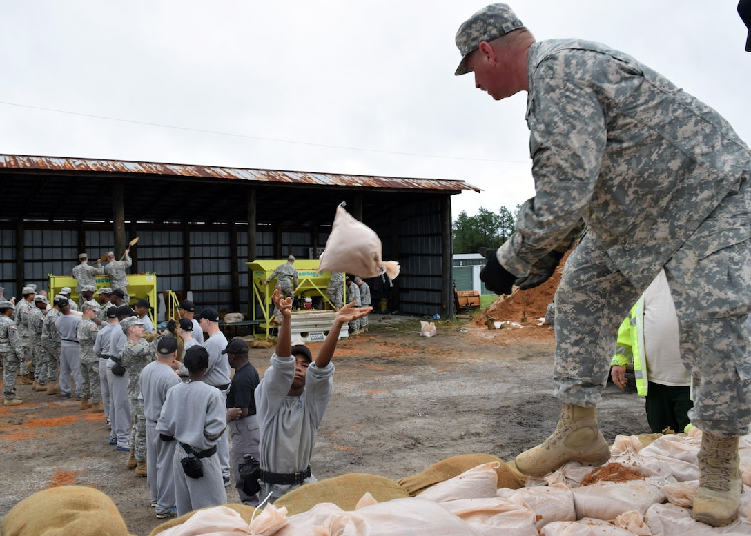A Youth Challenge Academy cadet tosses a sandbag to Army Cpl. Richard Wilson as he loads them onto a truck to assist in flood prevention in Augusta, Georgia, Oct. 4, 2015. Army National Guard photo by Capt. William Carraway
