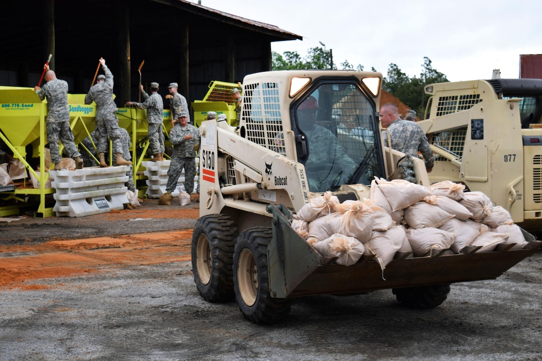 A soldier delivers a load of sandbags while guardsmen fill sandbags in anticipation of Hurricane Joaquin in Hephzibah, Georgia, Oct. 4, 2015. The Guardsmen are assigned to the 810th Engineer Company and 278th Military Police Company. Georgia Army National Guard photo by Capt. William Carraway 

