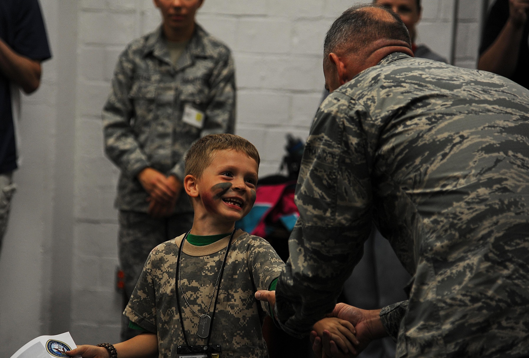 U.S. Air Force Col. Michael L. Downs, 17th Training Wing Commander, looks at a child’s mock battle wound during Operation K.I.D.S at Goodfellow Air Force Base, Oct. 3, 2015. Downs was present to send the children off with a motivational speech and to reward them with certificate of completion after their training. (U.S. Air Force photo by Airman Caelynn Ferguson/ Released)