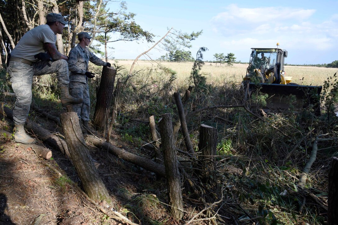 U.S. Air Force Airman 1st Class Tyler Herring and Senior Airman Blake Watkins, 35th Civil Engineer Squadron pavement and construction equipment journeymen, direct Airman Jeffrey Waldron, 35 CES pavement and construction equipment apprentice, in the removal of trees at Draughon Range, Japan, Sept. 29, 2015. This project provided 35 CES pavement and construction equipment Airmen the chance to gain experience with their equipment like the front-end loader. (U.S. Air Force Airman 1st Class Jordyn Fetter/Released)