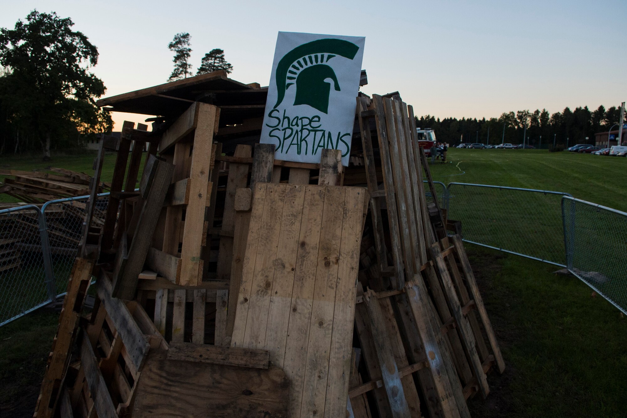 A pile of wood with a sign reading “SHAPE Spartans” waits to be burned for a bonfire after a Homecoming parade at Spangdahlem Air Base, Germany, Oct. 2, 2015. The Bitburg Middle High School Barons played the SHAPE High School Spartans for their homecoming football game Oct. 3, 2015, and won 32-7. (U.S. Air Force photo by Airman 1st Class Luke Kitterman/Released)    