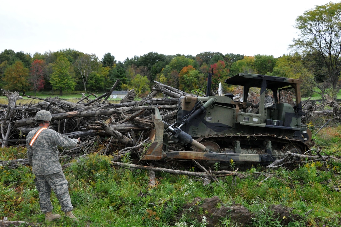 A soldier directs another soldier operating a bulldozer to clear space near Normanskill Creek in Albany, N.Y., Friday, Oct. 2, 2015 as part of New York's preparations for the possible landfall of Hurricane Joaquin. The soldier is assigned to the New York Army National Guard's 204th Engineer Battalion. 