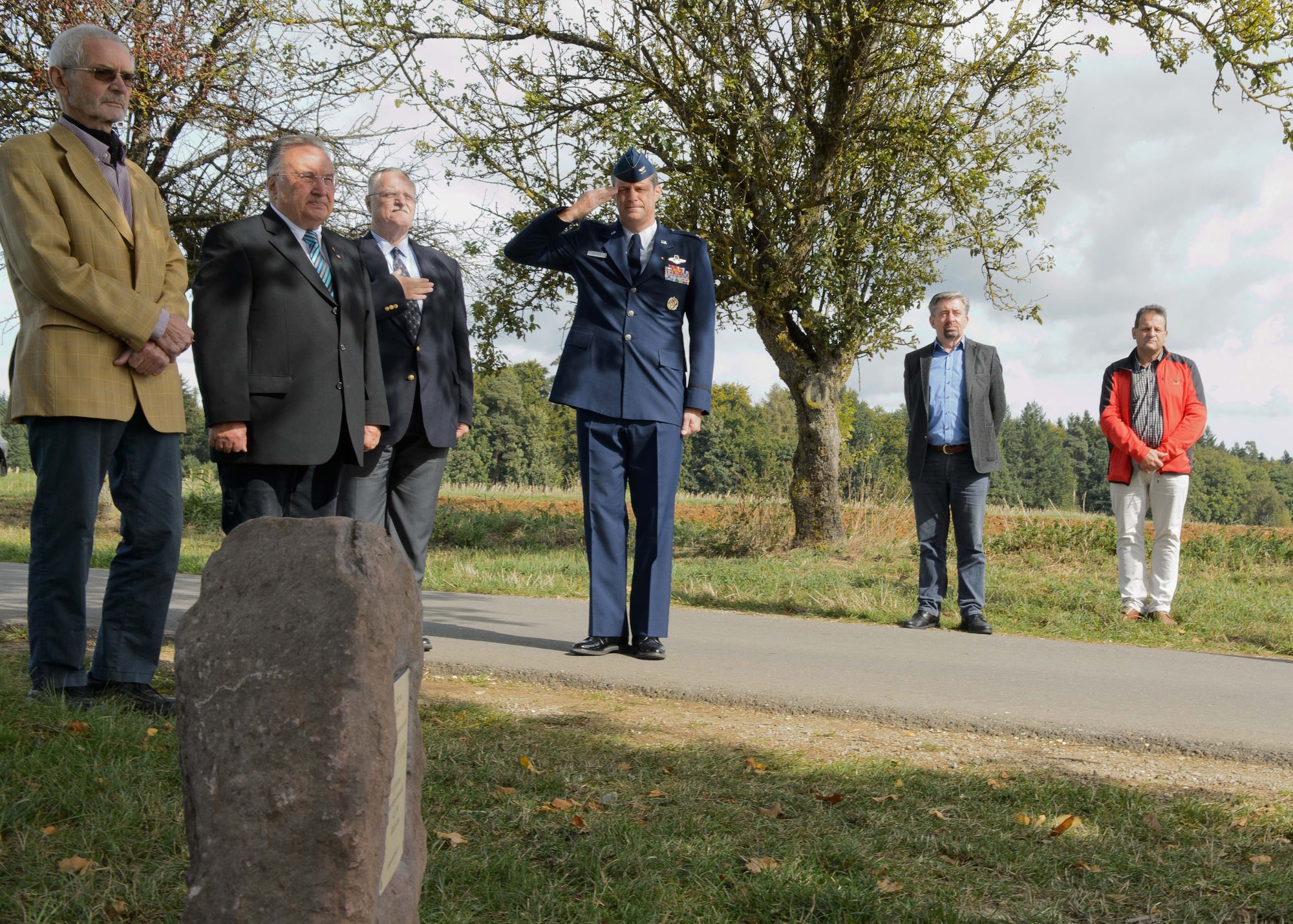 Col. Harry Benham, the U.S. Air Forces in Europe-Air Forces Africa operations and plans chief, salutes during the playing of taps during the revealing of a memorial stone for 2nd Lt. Priesley Cooper Jr. Sept. 25, 2015, in Dietingen, Germany. Cooper was conducting an escorting mission when his P-51D Mustang was shot down. The town of Dietingen buried him and 70 years later held a ceremony to honor him. (U.S. Air Force photo/Staff Sgt. Armando A. Schwier-Morales)