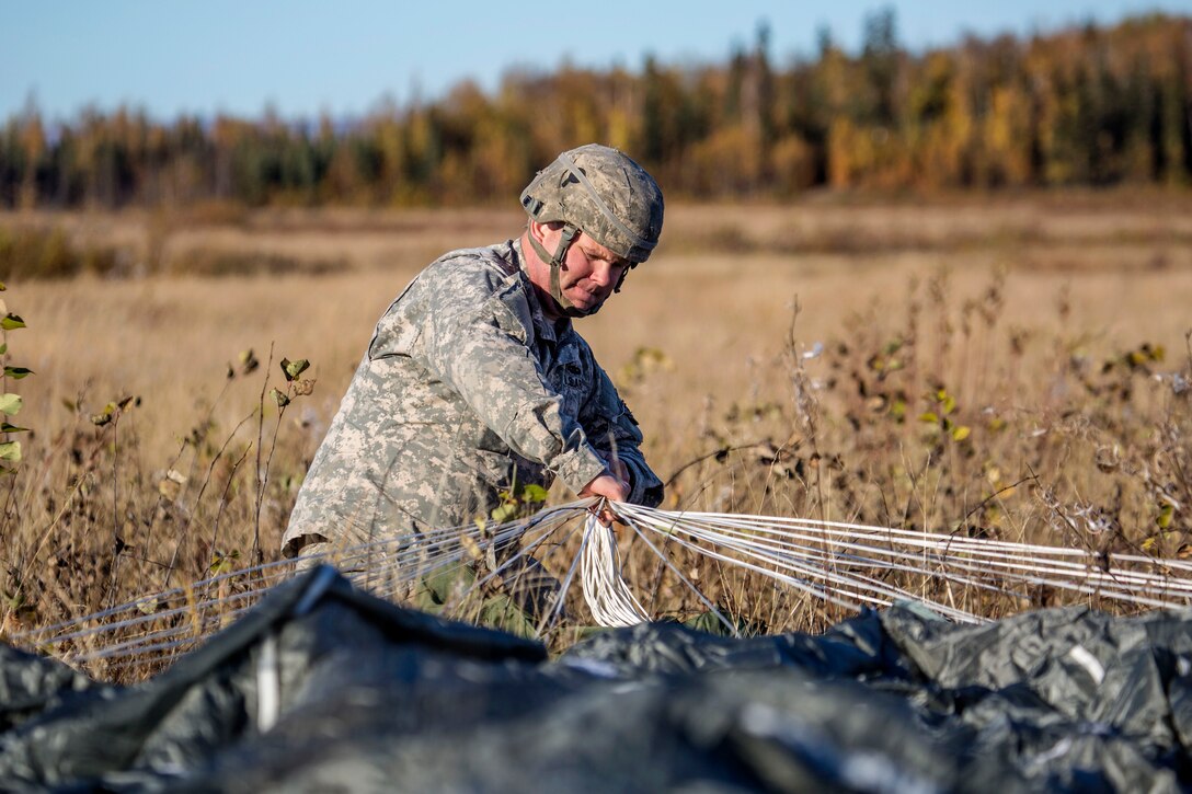 Army Pfc. Robert Manz recovers his parachute after conducting a helicopter jump on Malemute drop zone, Joint Base Elmendorf-Richardson, Alaska, Sept. 24, 2015.  Manz is assigned to Headquarters Battery, 2nd Battalion, 377th Parachute Field Artillery Regiment. U.S. Air Force photo by Alejandro Pena