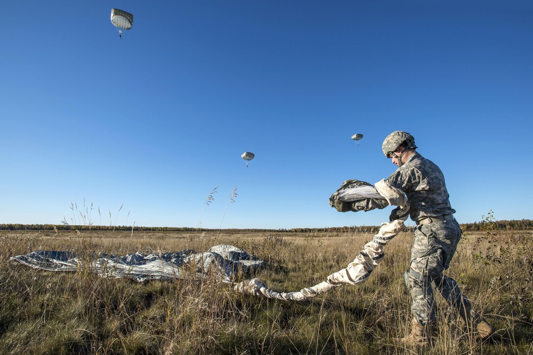 Army Spc. Conner Cota recovers his parachute after conducting a helicopter jump on Malemute drop zone, Joint Base Elmendorf-Richardson, Alaska, Sept. 24, 2015. Cota is assigned to Company E, 6th Brigade Engineer Battalion. U.S. Air Force photo by Alejandro Pena