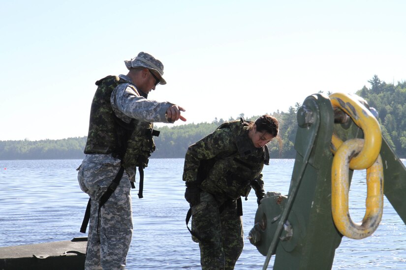 Sgt. 1st Class John Reyes of the Knoxville, Tenn., 1-100th Engineer Battalion helps instruct Canadian military engineer students as they learn to properly deploy a mobile floating bridge (MFB) during a training exercise at the Canadian Forces School of Military Engineering (CFSME) at Canadian Forces Base Gagetown in New Brunswick, Canada as part of an instructor exchange initiative between the U.S. and the CFSME, spearheaded by 1st Brigade Engineers out of Fort Leonard Wood, Mo.