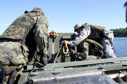 Sgt. 1st Class John Reyes of the Knoxville, Tenn., 1-100th Engineer Battalion helps Canadian military engineer students unhook and deploy a mobile floating bridge (MFB) during a training exercise at the Canadian Forces School of Military Engineering (CFSME) at Canadian Forces Base Gagetown in New Brunswick, Canada, as part of an instructor exchange initiative between the U.S. and the CFSME, spearheaded by 1st Brigade Engineers out of Fort Leonard Wood, Mo.