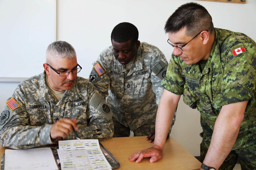 Sgt. 1st Class Hector Torruella of the 1st Battallion, 95th Engineer Regiment (1-95 EN) and Sgt. 1st Class Oniel Murray of the Fort Leonard Wood, Mo., 1st Brigade Engineers work with one of their Canadian counterparts while converting measurements to the metric system at the Canadian Forces School of Military Engineering (CFSME) at Canadian Forces Base Gagetown in New Brunswick, Canada, as part of an instructor exchange initiative between the U.S. and the CFSME, spearheaded by 1st Brigade engineers.