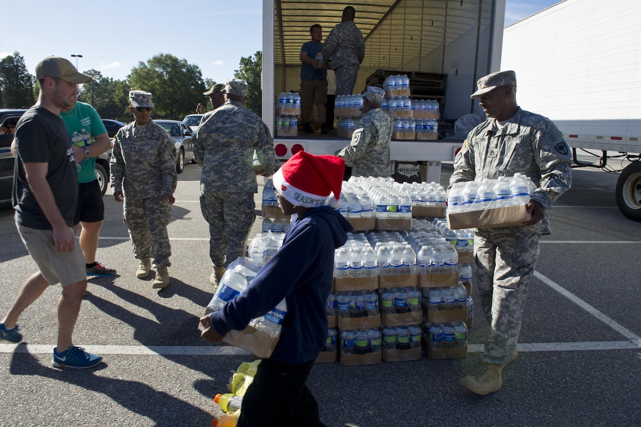 South Carolina Army National Guardsmen from the 742nd Maintenance Company, law enforcement personnel and volunteers distribute drinking water to residents affected by flooding caused by Hurricane Joaquin in Columbia, S.C., Oct. 6, 2015. South Carolina Air National Guard photo by Tech. Sgt. Jorge Intriago