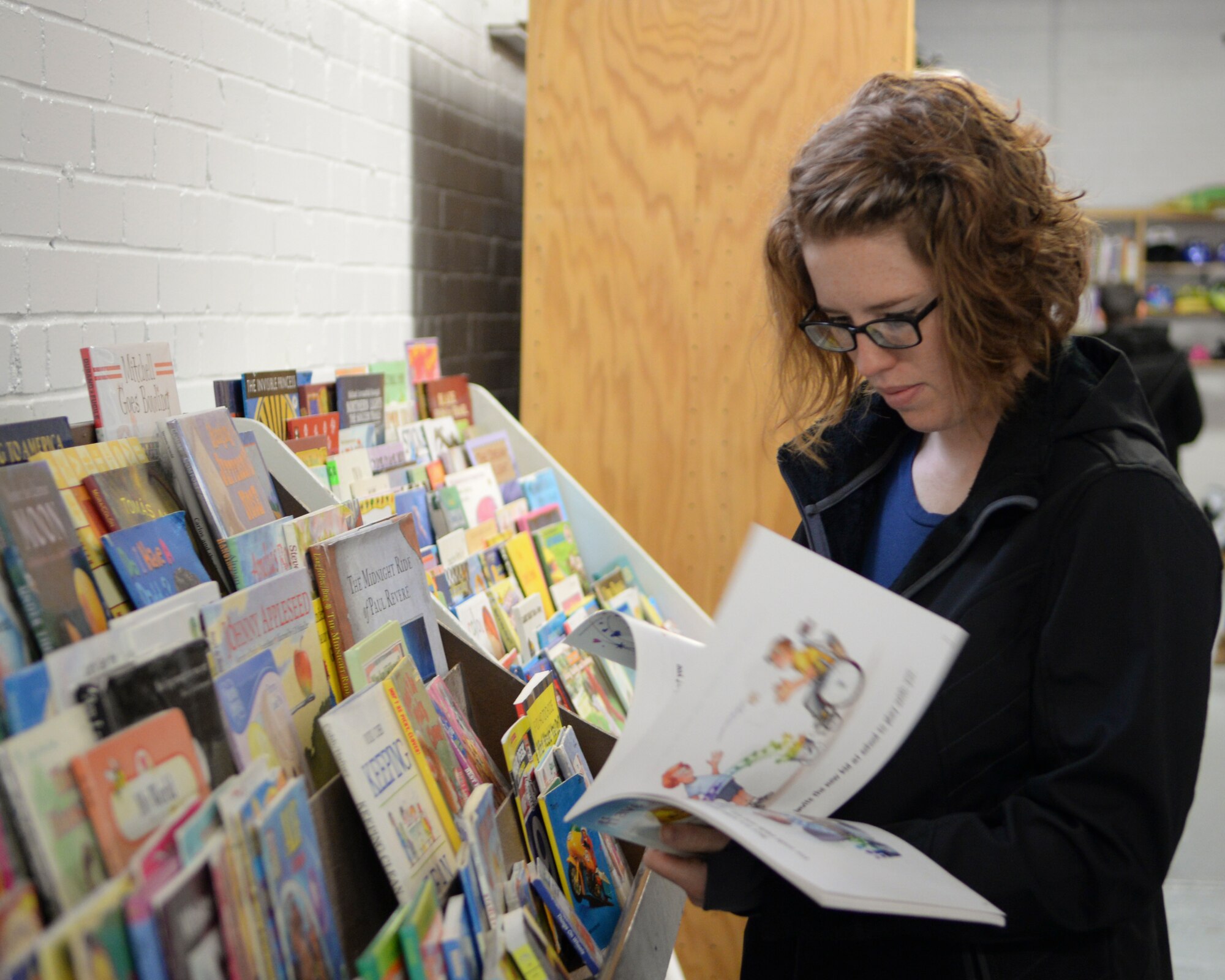 Airman 1st Class Elizabeth Richards, 90th Communications Squadron, browse through children books during the grand re-opening of the Airmen’s Attic on F.E. Warren Air Force Base, Wyo., Oct. 3, 2015. The Airmen’s Attic is stocked by donated items from the community, and all items are free. (U.S. Air Force photo by Airman 1st Class Malcolm Mayfield)