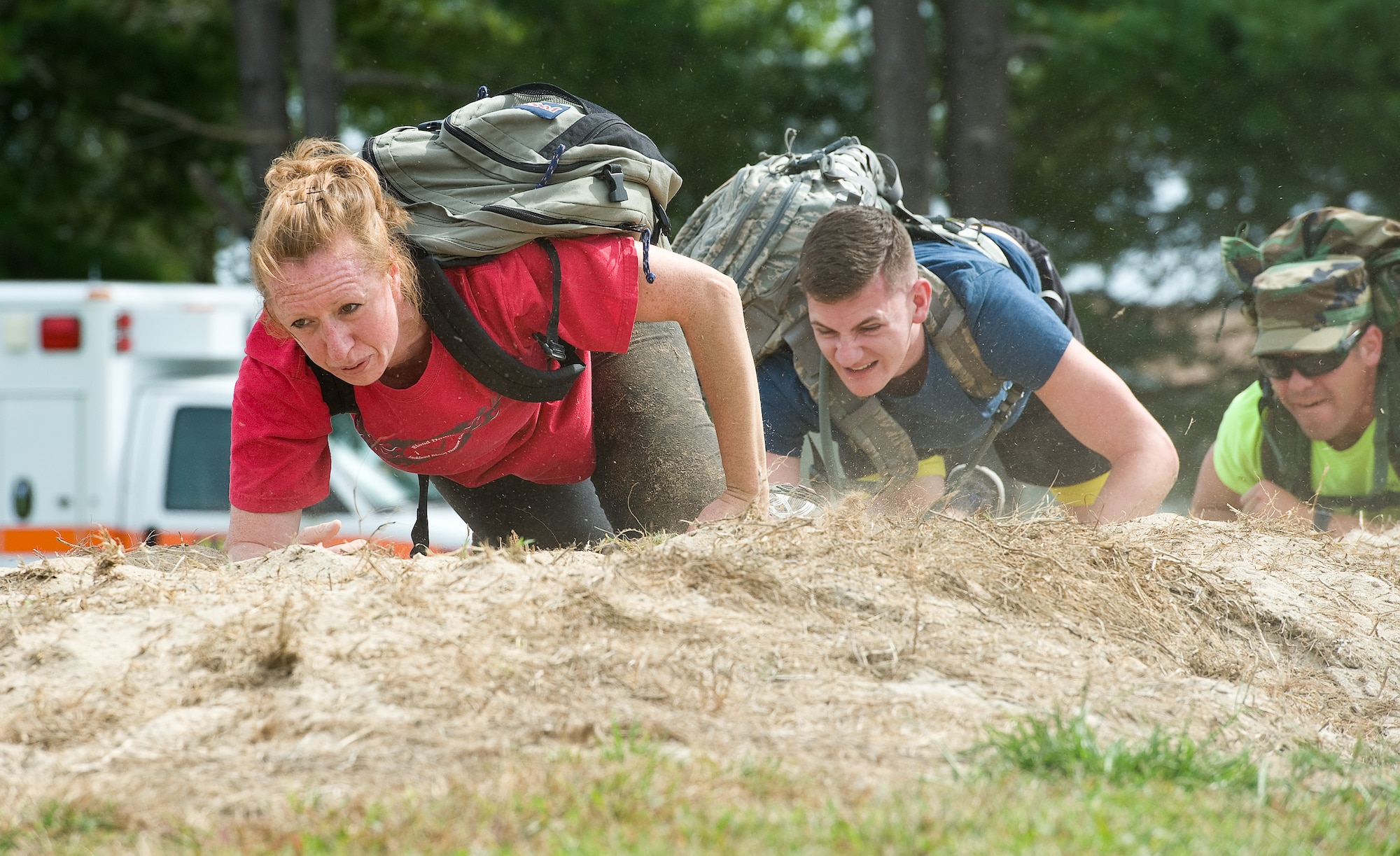 Tech. Sgt. Stephanie Ambler, Armed Forces Medical Examiner System laboratory technician, left, crawls along a dirt mound during the GORUCK Light team cohesion challenge Sept. 25, 2015, on Dover Air Force Base, Del. Ambler stated at the completion of the five-hour-long challenge led by a former U.S. Marine Corps reconnaissance member,  that she was physically tired but mentally proud of herself. (U.S. Air Force photo/Roland Balik)