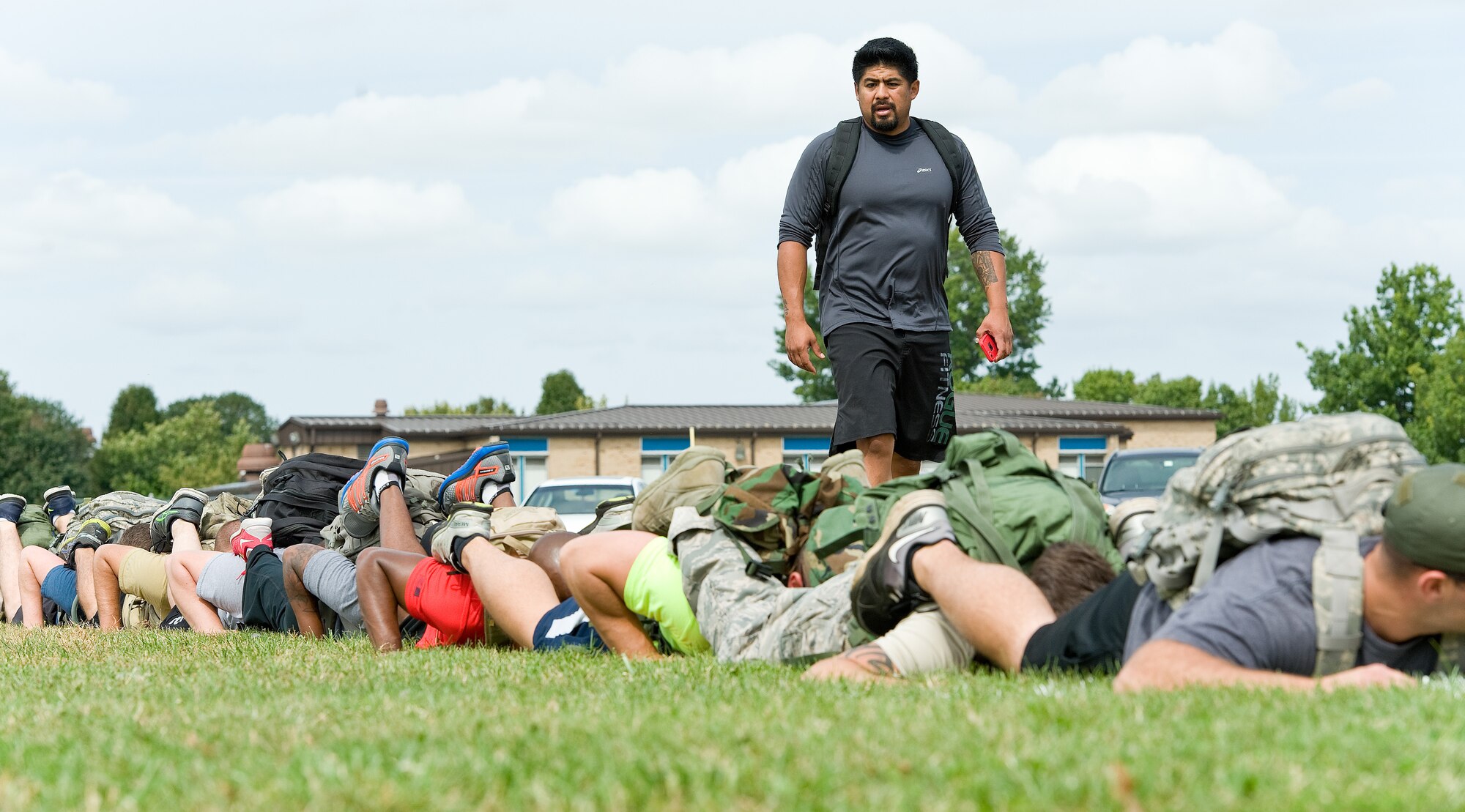 Chris Stokes, GORUCK Light qualified cadre, standing, instructs 31 participants on a team push-up challenge Sept. 25, 2015, on Dover Air Force Base, Del. During the five-hour-long GORUCK Light team cohesion challenge, Stokes, a former U.S. Marine Corps reconnaissance member, presented Team Dover members with numerous physical challenges along a 7.8-mile course as they learned to overcome adversity by working as a team. (U.S. Air Force photo/Roland Balik)
