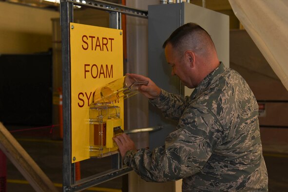 Col. Brian McDaniel, 92nd Air Refueling Wing commander, initiates the foam suppression system test in hangar one Oct. 1, 2015, at Fairchild Air Force Base, Wash. The foam suppression system is capable of producing 238,000 cubic feet of foam concentrate per minute. In the test, the system ran for approximately two-and-half-minutes, and produced over six feet of foam which covered the 68,000 square foot floor of hangar one.