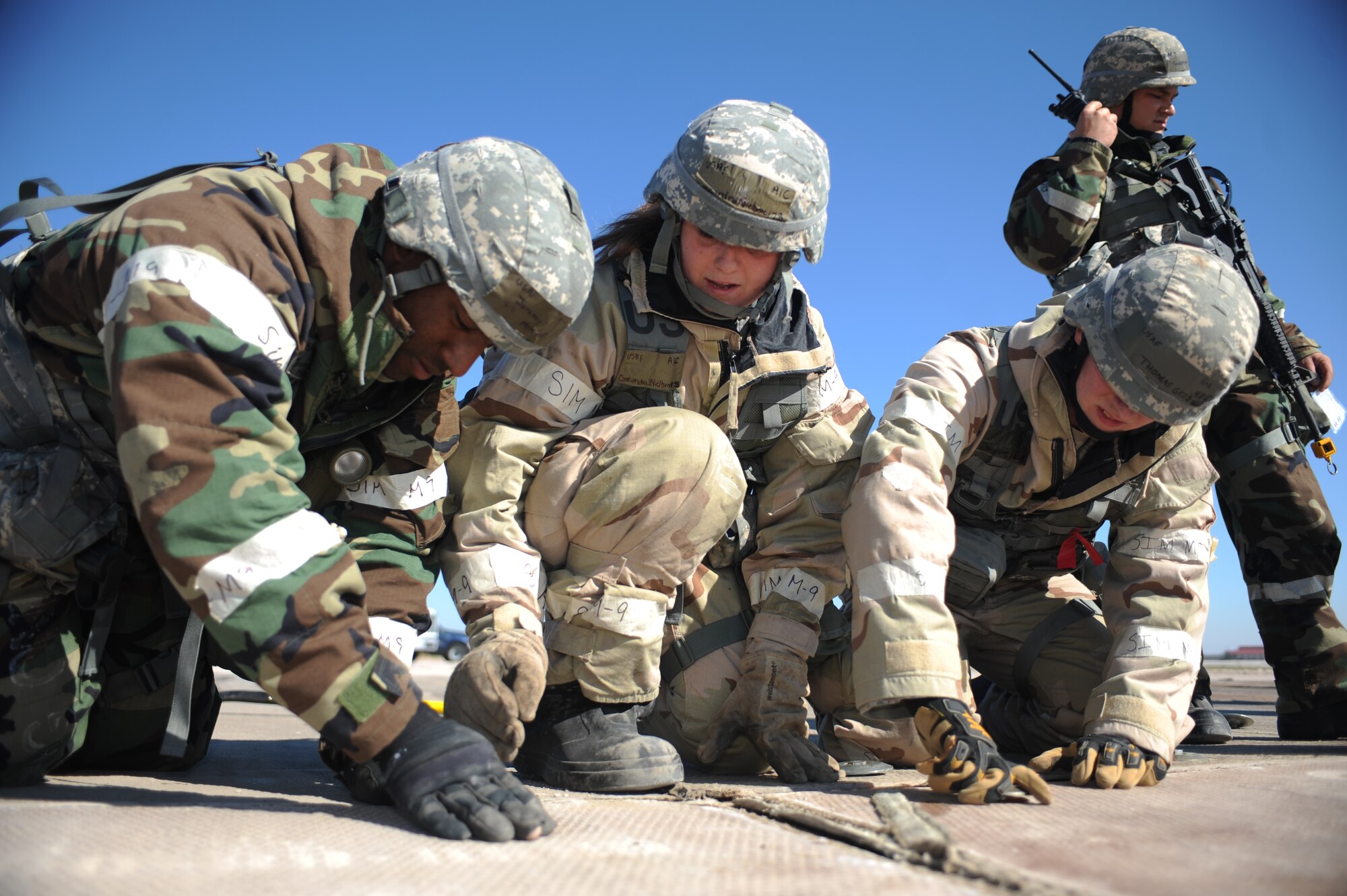 Airmen 1st Class Jeremy Mitchell, left, and Cassandra Nielson, center, and Senior Airman Thomas Goss, right, 28th Civil Engineer Squadron pavements and construction heavy equipment operators, tighten bushings to fasten a fiber glass mat to a splice at Ellsworth Air Force Base, S.D., Sept. 30, 2015. The fiberglass mat is used to cover any craters on an airfield and provides a clean and flat surface for aircraft to take off from without worry of foreign objects being sucked into the engines. (U.S. Air Force photo by Airman Sadie Colbert/Released)