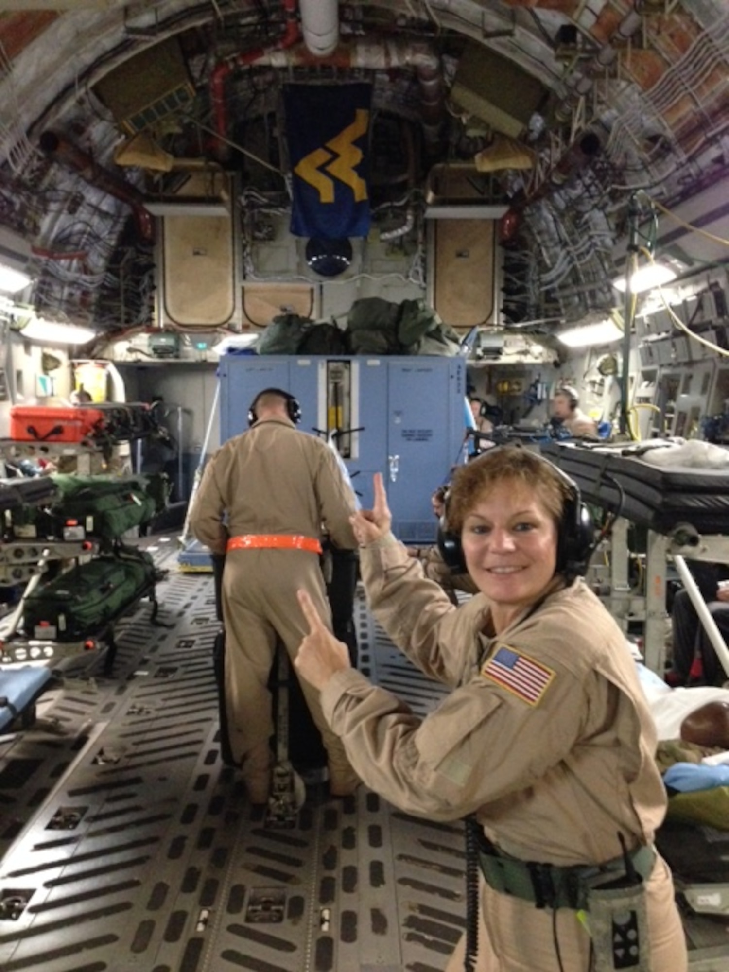 Tech. Sgt. Christine Cournoyer, an aeromedical technician with the 167th Aeromedical Evacuation Squadron based at the 130th Airlift Wing, Charleston, W.Va., proudly points to the Mountaineer flag while taking care of patients alongside a Wyoming Air National Guard AES crew. Cournoyer was the sole West Virginia Air National Guard aeromedical technician to fly aboard a C-17 Globemaster III piloted by a 167th aircrew during a recent aeromedical evacuation mission.