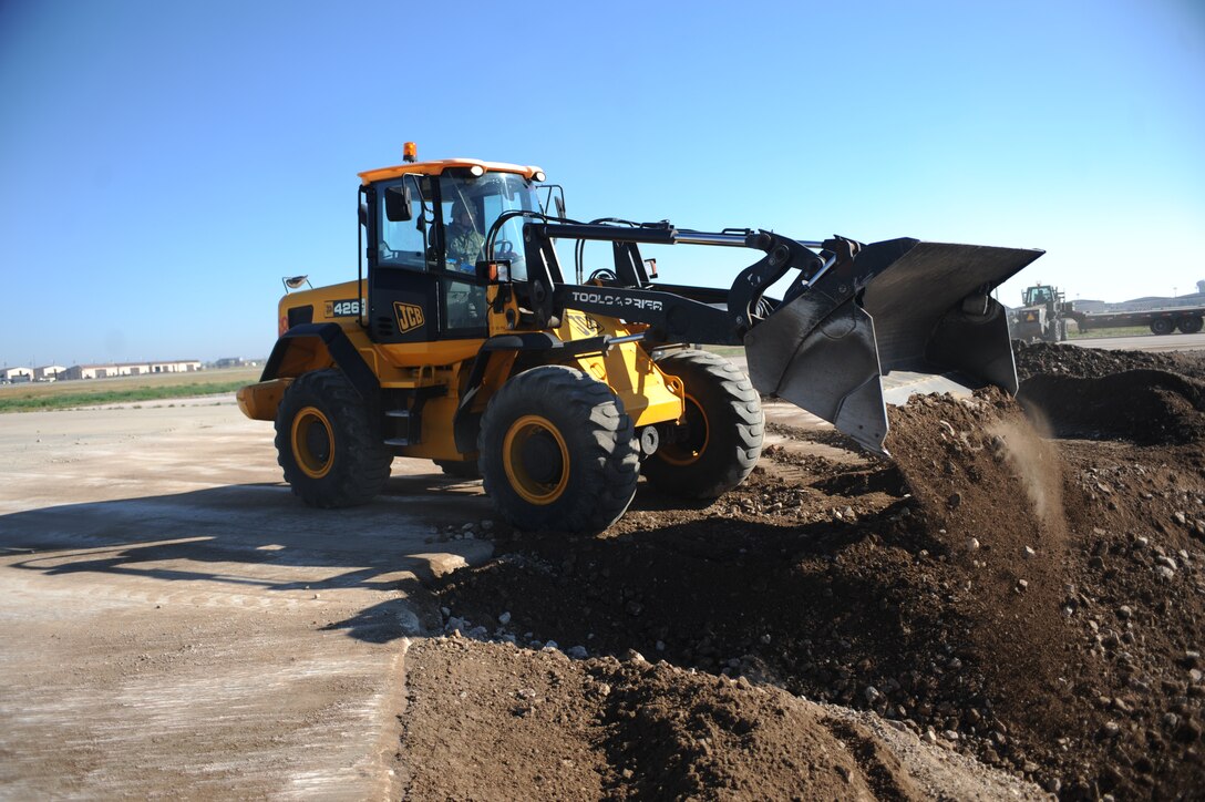Senior Airman Dustin Snyder, 28th Civil Engineer Squadron pavements and construction heavy equipment operator, uses a front-end loader to fill a crater on a simulated runway at Ellsworth Air Force Base, S.D., Sept. 30, 2015. The squadron held a speed training exercise designed to improve execution time as well as hone operation precision and performance standards, all while reviewing basic safety procedures. (U.S. Air Force photo by Airman Sadie Colbert/Released)