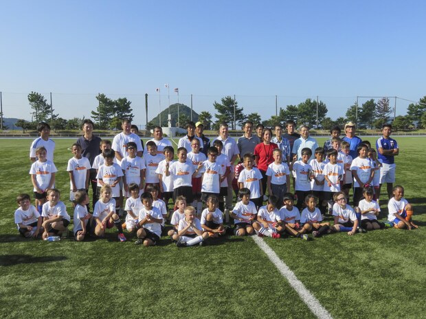 Japanese and American children, coaches and government officials pose for a picture the Japan-U.S. Friendship Kid's Soccer Event coordinated by the Chugoku-Shikoku Defense Bureau at the Suo-Oshima Town Athletics Track and Field in Yamaguchi Prefecture, Japan, Sept. 27, 2015. Twenty-five children from the station, ages 7-10, integrated with 20 Japanese children from schools in the local area to learn about each other’s culture, do warm up drills and compete in a tournament. This soccer meet gave the opportunity for the children to interact, which helps strengthen the friendship between the Japanese and Americans.