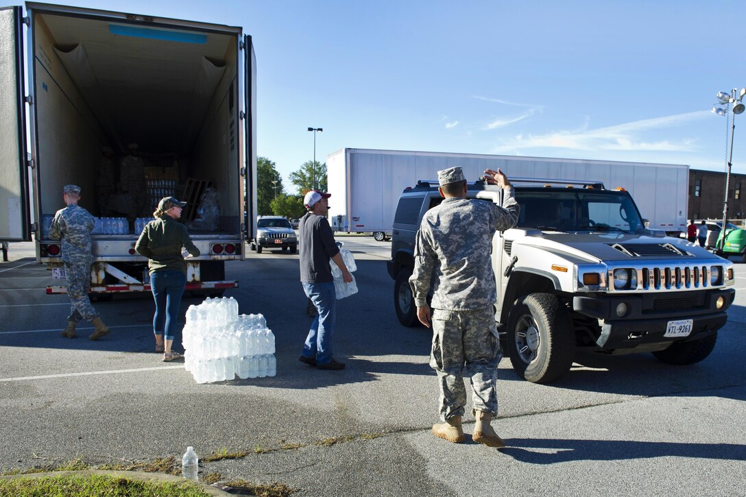 Soldiers work alongside local law enforcement and volunteers to distribute drinking water to residents affected by heavy rainfall caused by Hurricane Joaquin at the Lower Richland High School, Columbia, S.C., Oct. 6, 2015. The soldiers are assigned to the South Carolina Army National Guard’s 742nd Maintenance Company. The South Carolina National Guard has also been activated to support state and county emergency management agencies and local first responders as historic flooding impacts counties statewide. South Carolina Air National Guard photo by Tech. Sgt. Jorge Intriago