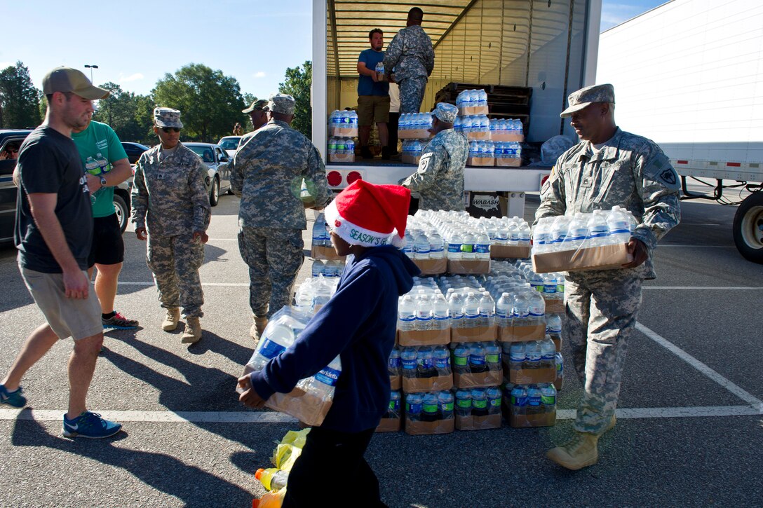 Soldiers work alongside local law enforcement and volunteers to distribute drinking water to residents affected by heavy rainfall caused by Hurricane Joaquin at the Lower Richland High School, Columbia, S.C., Oct. 6, 2015.  