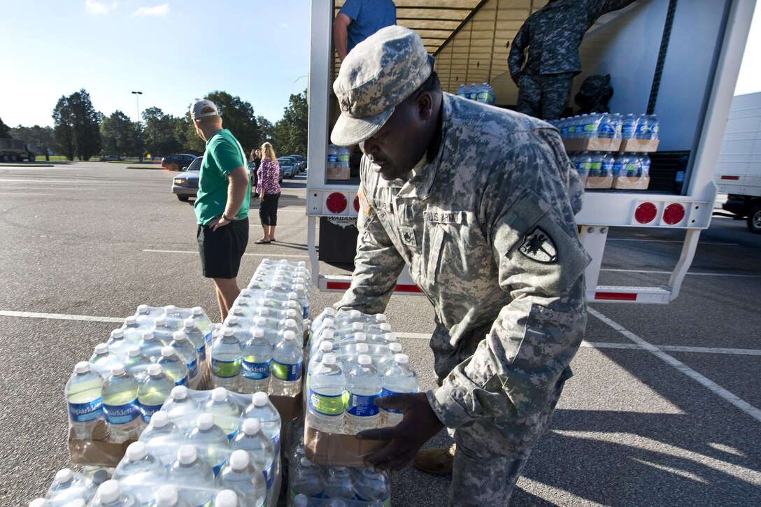 Army Staff Sgt. John C. Williams distributes drinking water to residents affected by heavy rainfall caused by Hurricane Joaquin at the Lower Richland High School, Columbia, S.C., Oct. 6, 2015. Williams is assigned to the South Carolina Army National Guard's 742nd Maintenance Company. South Carolina Air National Guard photo by Tech. Sgt. Jorge Intriago