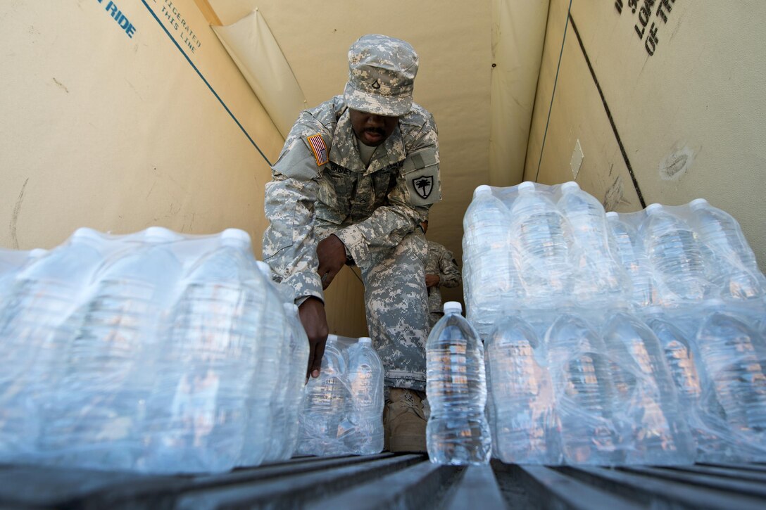Army Pfc. Daquan Dabney works with local law enforcement and volunteers to distribute drinking water to residents affected by heavy rainfall caused by Hurricane Joaquin at the Lower Richland High School, Columbia, S.C., Oct. 6, 2015. Dabney is assigned to the South Carolina Army National Guard's 742nd Maintenance Company. South Carolina Air National Guard photo by Tech. Sgt. Jorge Intriago