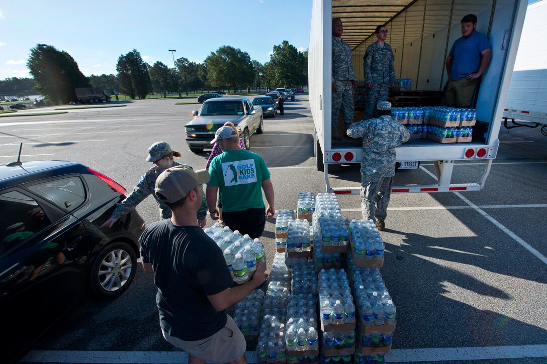 Soldiers work with local law enforcement and volunteers to distribute drinking water to residents affected by heavy rainfall caused by Hurricane Joaquin at the Lower Richland High School, Columbia, S.C., Oct. 6, 2015. South Carolina Air National Guard photo by Tech. Sgt. Jorge Intriago