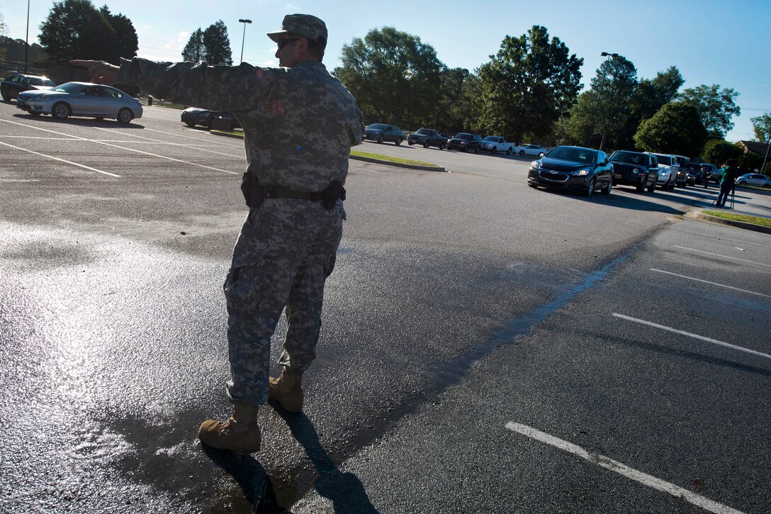 Army Staff Sgt. Glenn Maier directs traffic to points of distribution for drinking water at Lower Richland High School, Columbia, S.C., Oct. 6, 2015. Maier is a provost marshal assigned to the South Carolina State Guard. South Carolina Air National Guard photo by Tech. Sgt. Jorge Intriago

