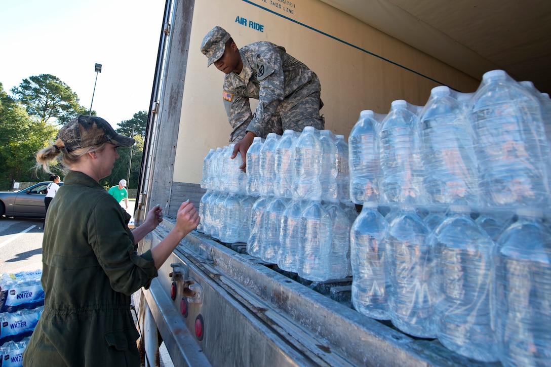 Army Spc. Frank Williams works with a volunteer to distribute drinking water to residents affected by heavy rainfall caused by Hurricane Joaquin at the Lower Richland High School, Columbia, S.C., Oct. 6, 2015. Williams is assigned to the South Carolina Army National Guard's 742nd Maintenance Company. South Carolina Air National Guard photo by Tech. Sgt. Jorge Intriago