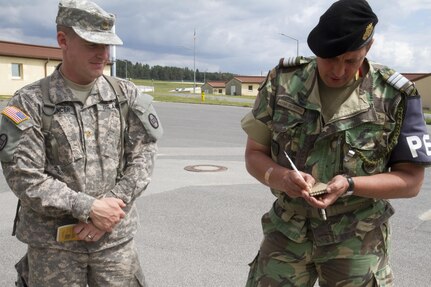 Maj. Jason Spencer, the 30th Armored Brigade Combat Team safety officer, speaks with Lt. Col. Nuno Lourenco Alvares Alves de Sousa, a fire phobia instructor for the Portuguese army military police, during fire phobia training June 16 in Hohenfels, Germany. This exercise is designed to help peacekeeping troops actively go through the steps of what to do when Molotov cocktails are encountered during crowd and riot control.