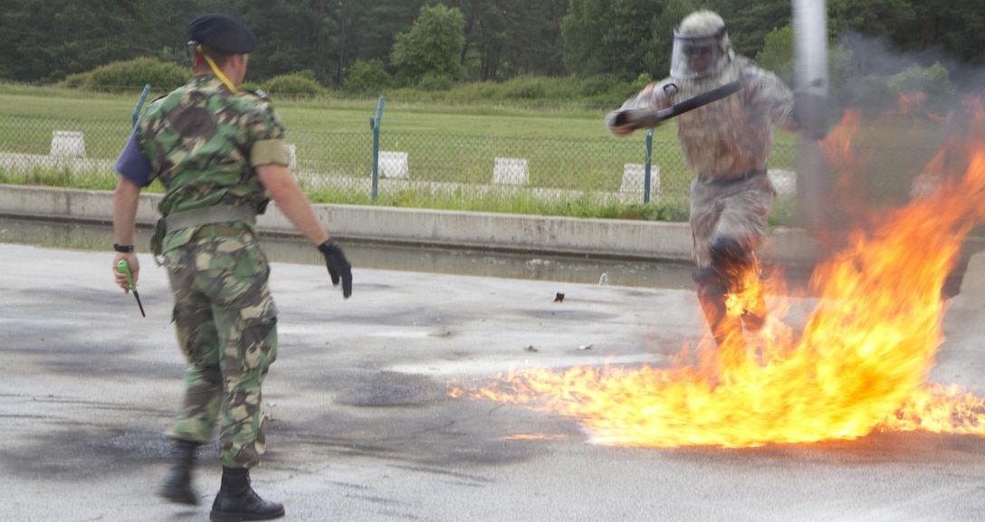 Spc. Mario Strickland with the 1st Battalion, 252nd Armor Regiment’s Alpha Company 2nd Platoon, maneuvers his way through flames of a broken Molotov cocktail thrown by a member of the Portuguese army military police during fire phobia training June 16 in Hohenfels, Germany. This exercise is designed to help peacekeeping troops actively go through the steps of what to do when Molotov cocktails are encountered during crowd and riot control.