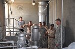 Defense Logistics Agency Director Air Force Lt. Gen. Andy Busch (right) listens to Royal Bahraini Air Force Lt. Col. Abdulla Abdullaare (second from right) during a May 17 tour of the Bahraini Air Force Fuel Pump House at Isa Air Base, Bahrain. May 17.