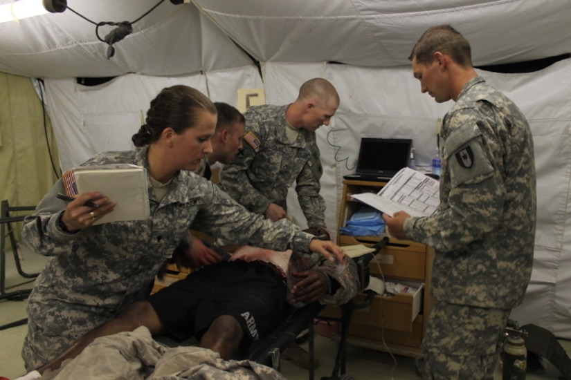 Spc. Brittany Hall, Spc. Aaron Smith, and Staff Sgt. Christopher Langland (left to right) with the 345th combat support hospital, examine an injured Soldier in a mass casualty training exercise June 3 at Fort Hood, Texas. The exercise was conducted for pre-mobilization training before leaving on a peacekeeping mission to Kosovo. (U.S. Army photo by Sgt. Erick Yates)