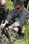 Spc. Aaron Smith, a licensed practical nurse with the 345th Combat Support Hospital, gives instructions to troops from the Romanian army’s 26th Mountain Battalion, during a medical evacuation exercise at the Joint Multinational Readiness Center in Hohenfels, Germany, June 19. The purpose of the training was for U.S. Soldiers to share medical evacuation techniques with multinational forces (U.S. Army photo by Sgt. Erick Yates)
