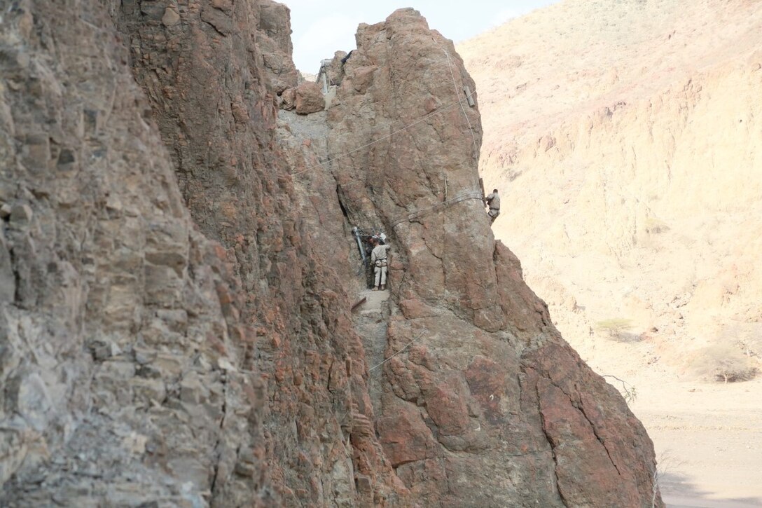 ARTA BEACH, Djibouti (Sept. 27, 2015) U.S. Marines with the 15th Marine Expeditionary Unit navigate across a cliff-face during a desert survival course with the French 5th Overseas Combined Arms Regiment (RIAOM). Elements of the 15th MEU are training with the 5th RIAOM in Djibouti in order to improve interoperability between the MEU and the French military. (U.S. Marine Corps photo by Sgt. Steve H. Lopez/Released)