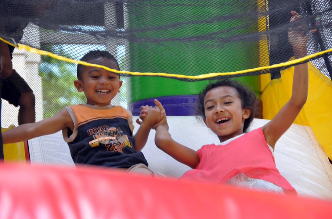 FORT BELVOIR, Va. (June 24, 2015) Seven-year-old Bianca Mata and 3-year-old brother Jeremiah hold hands while coming down a bounce house slide at the 2015 HQC Family Day June 24 at the McNamara Headquarters Complex. The annual event allows HQC employees to bring their families to work for fun and camaraderie.