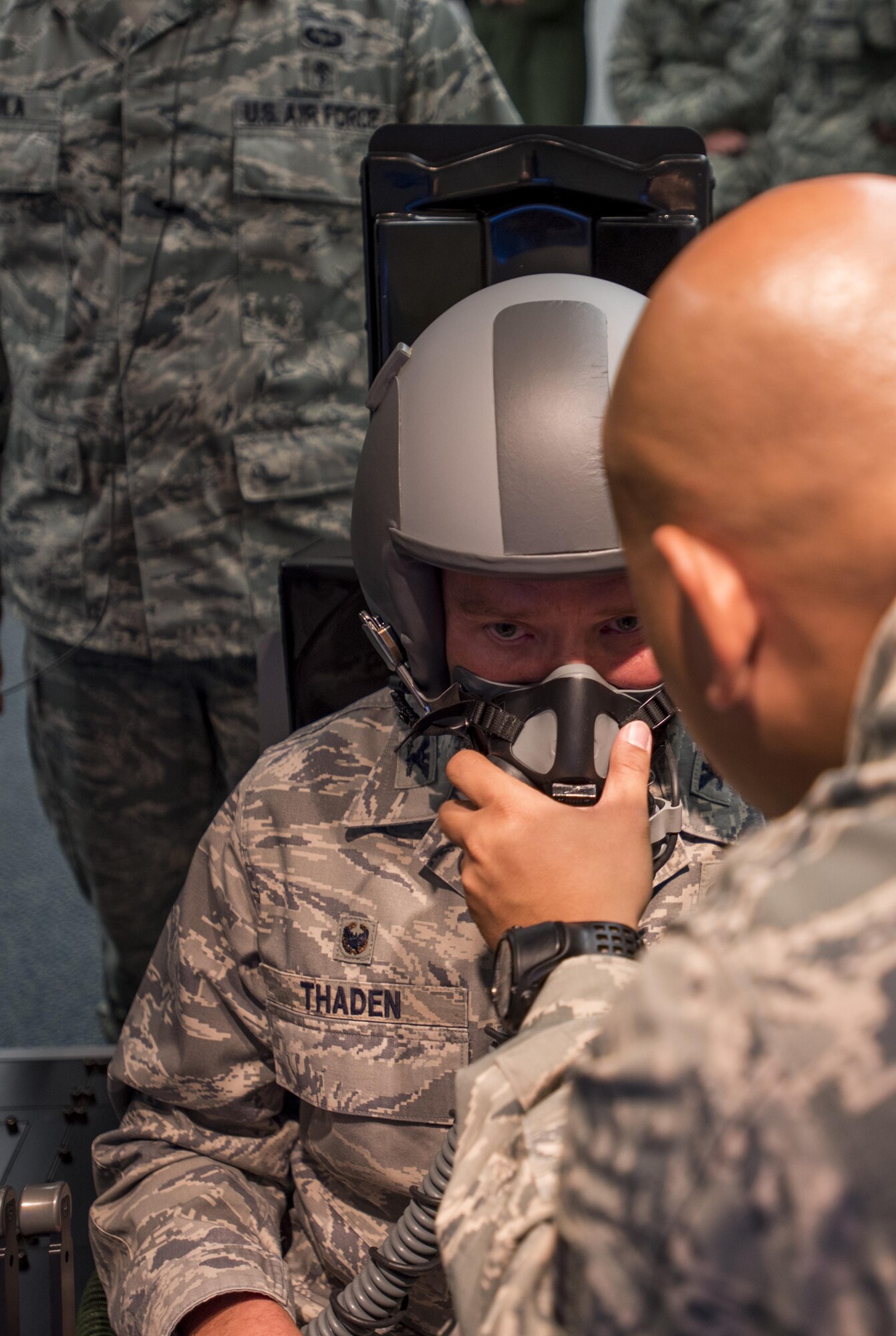 Staff Sgt. Nazareth Oliver, 87th Aerospace Medicine Squadron physiologist, helps Col. Frederick D. Thaden, Joint Base McGuire-Dix-Lakehurst and 87th Air Base Wing commander, don a flight helmet and mask before demonstrating a hypoxia training system during its unveiling at JB MDL, N.J., Sept. 21, 2015. The altitude chamber previously used has a vacuum that removes the pressure to mimic pressure in flight at 25,000 feet, where the new one-person simulator uses a mixture of nitrogen and air brought in by gas cylinders through the reduced oxygen breathing device.