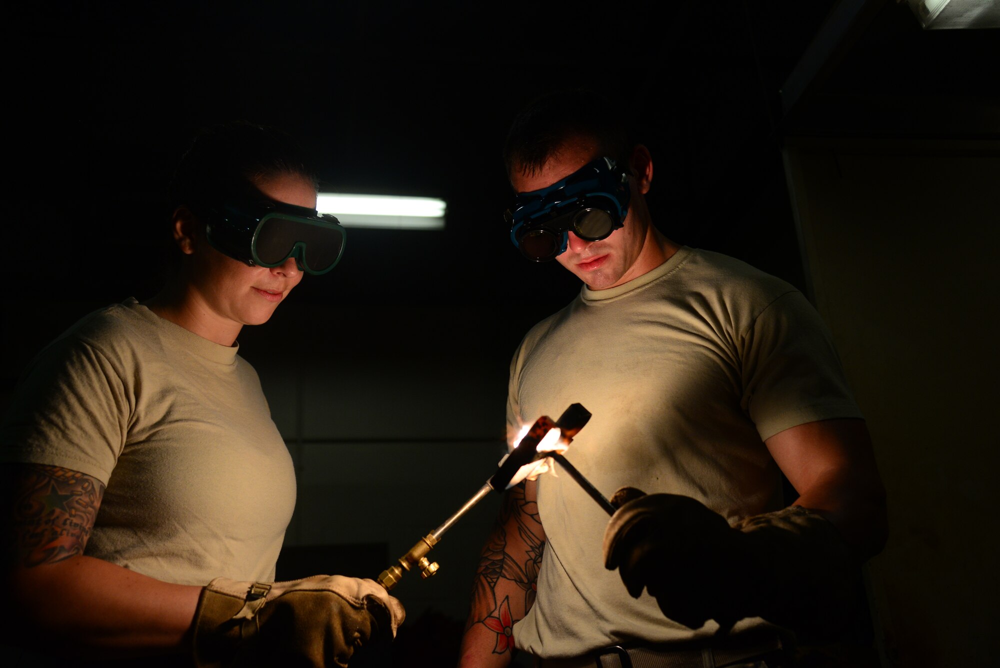 Staff Sgt. Bethanie Jeremenko, a 51st Civil Engineer Squadron structural craftsman, works with Senior Airman Dale Briggs, 51st CES structural journeyman, using an industrial blow torch to heat up an iron brand created as part of a special project at Osan Air Base, Republic of Korea, July 30, 2015. A structures troop acts as a functional artisan who can create with a plethora of materials ranging from concrete and carpentry to metal work. 
(U.S. Air Force photo/Staff Sgt. Amber Grimm)