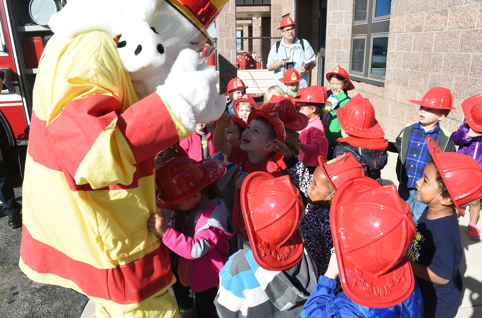 Sparky the Fire Dog greets children from the Crested Butte Child Development Center Oct. 7, 2015, on Buckley Air Force Base, Colo. Sparky was part of a visit from the Buckley Fire Department to both CDCs on base to spread the word about Fire Prevention Week. The fire department also brought fire trucks for the children to look at, along with plastic fire helmets and coloring books for them to take home. (U.S. Air Force photo by Airman 1st Class Samantha Meadors/Released)