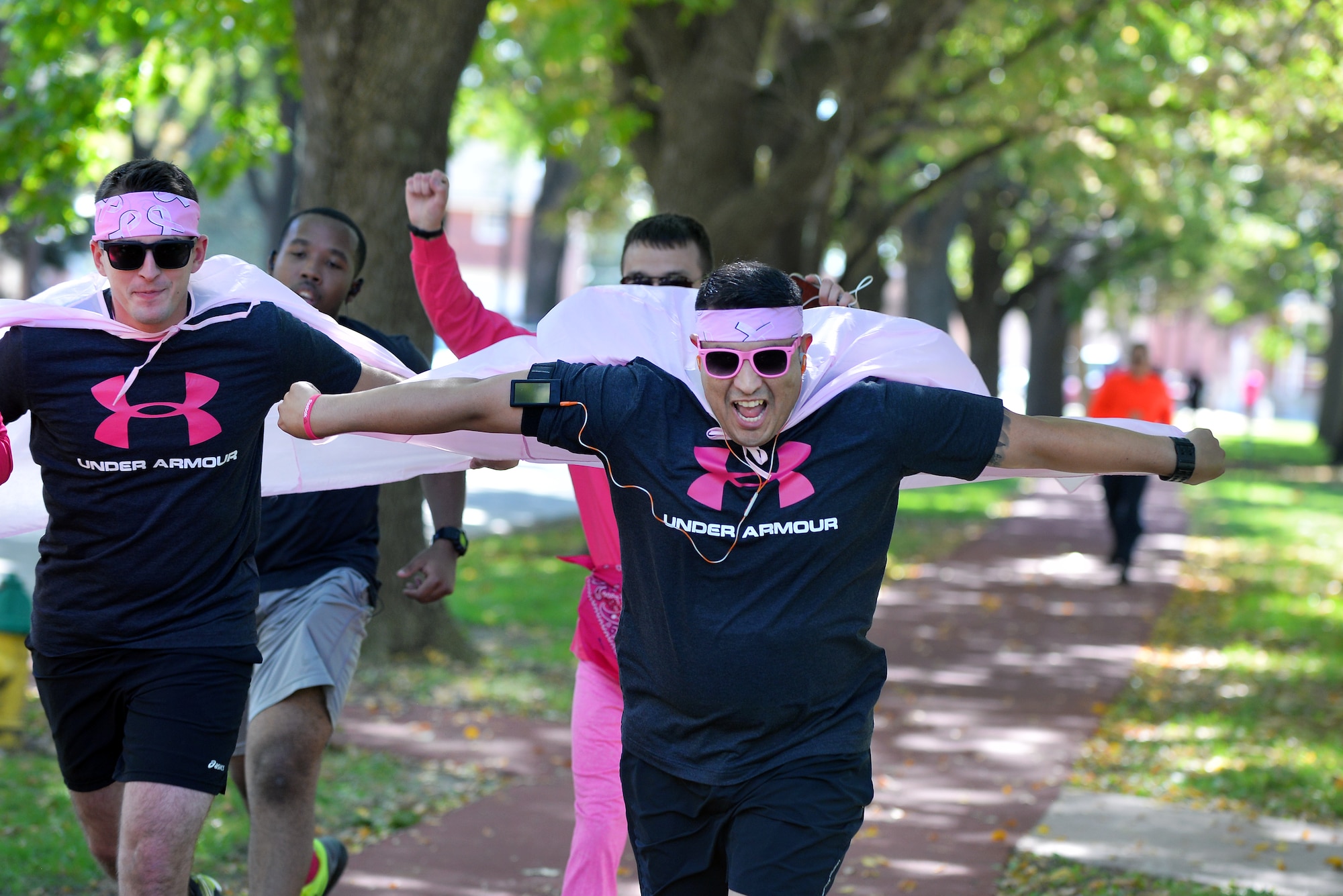 Staff Sgt. Adrian Chavez, 55th Medical Support Squadron, and Staff Sgt. Samuel Fickel, 55th MDSS, let their pink capes fly as they complete the first of four laps around the Offutt Air Force Base parade grounds Oct. 2 for the first Breast Cancer Awareness 5K.  Festive wear was a common theme as runners donned their pink gear for the run.  (U.S. Air Force photo by Josh Plueger/Released)